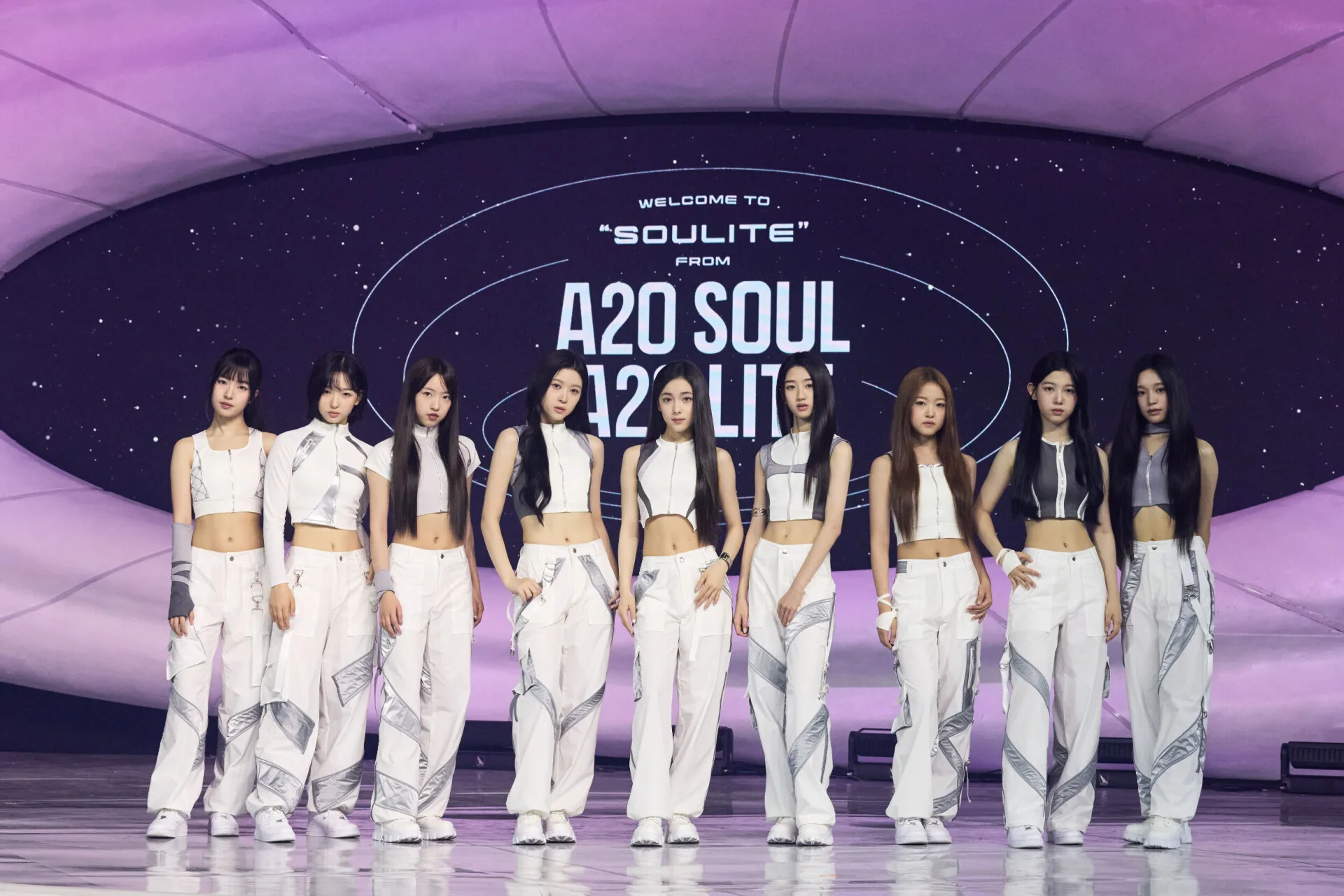 The nine members of A2O LITE in white and silver stage outfits posing in a row at their debut showcase at KINTEX on October 12, 2026