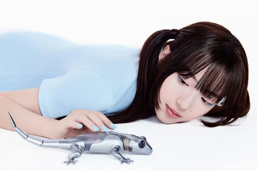 Xili of A2O LITE lying on the floor beside a small silver robotic lizard, in her official NEON artwork
